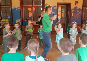 dzieci śpiewają piosenkę o wiośnie, stojąc wokół prowadzącej nauczycielki